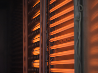 Close-up of glowing infrared heating elements inside an industrial system, emitting orange lights.