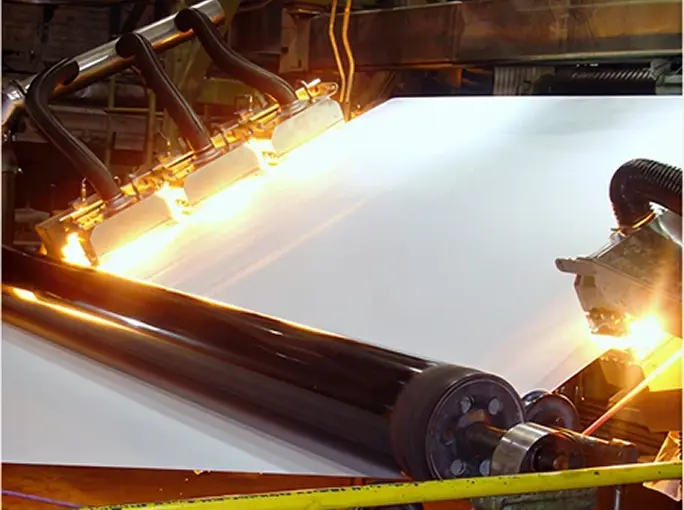 Infrared drying units heating a moving paper web on an industrial machine.