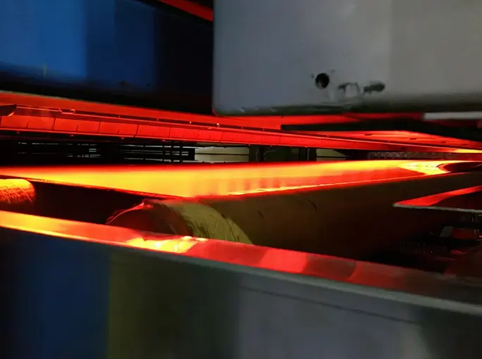 Infrared drying system heating a paper web on an industrial roller.