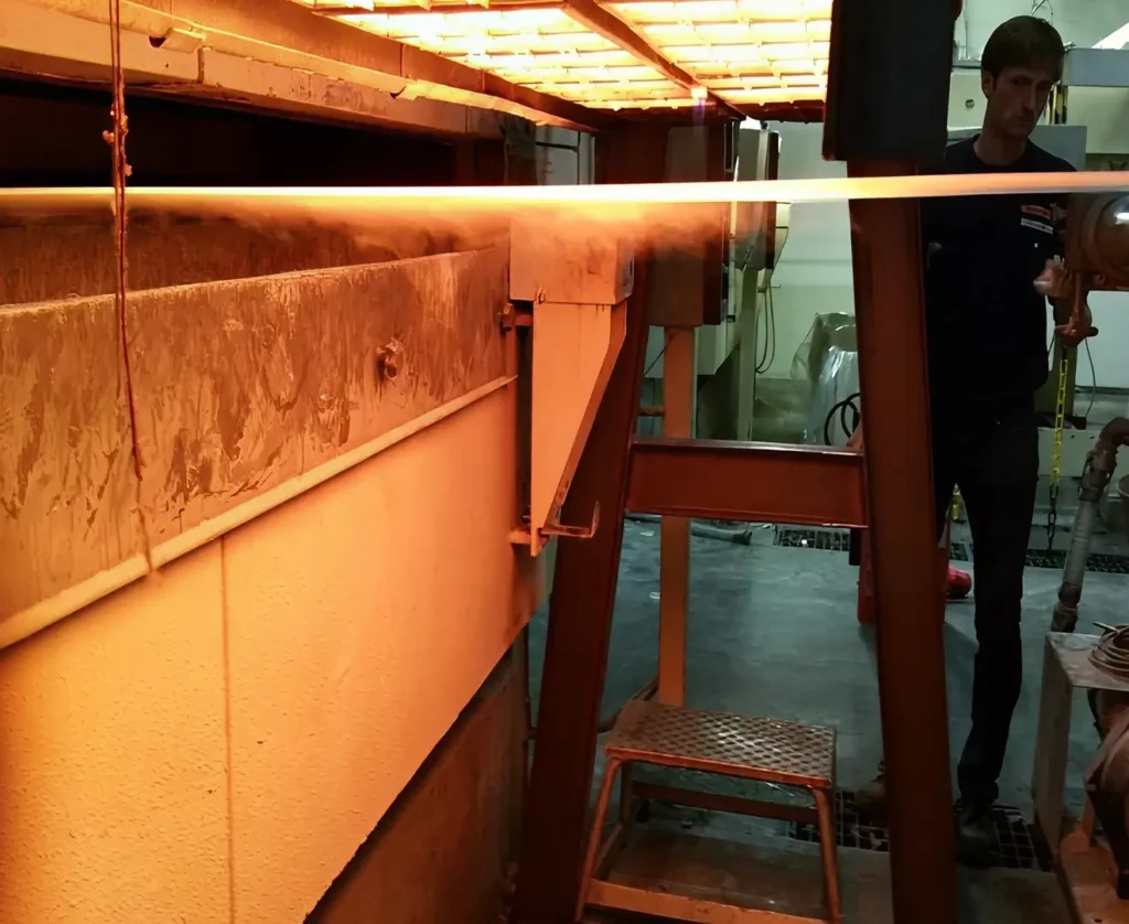 Worker operating infrared heating equipment in an industrial setting.