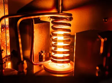 Heated metal spring emitting orange light within a machine.