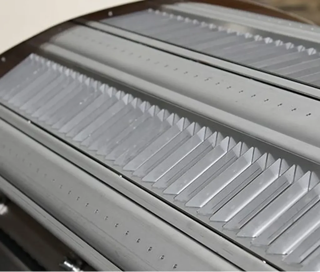 Close-up of metallic panels with evenly spaced ridges and perforations