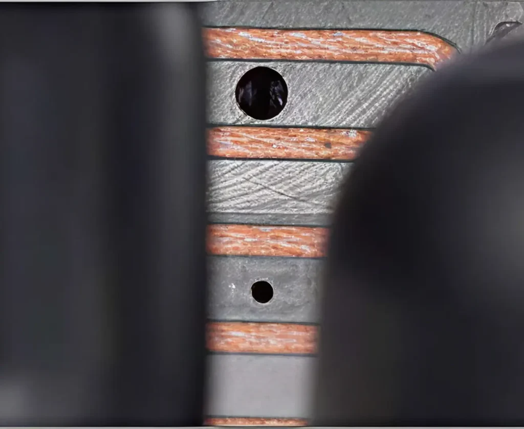 Close-up of metal surface with copper tubing and circular holes.